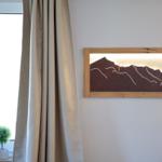 Wandbild mit Bergmotiv, Vorhang und Pflanze vor Fenster