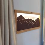 Hölzernes Wandbild mit Bergsilhouette und eingebauter Beleuchtung an der Wand.