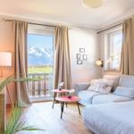Wohnzimmer mit Sofa, TV und Balkonblick auf Berge