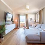 Wohnzimmer mit Sofa, TV und Balkonblick.