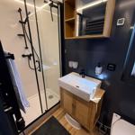Bathroom with shower, sink, and toilet. Wooden and metal accents.