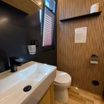 Bathroom with sink, toilet, and wooden wall cladding.
