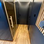 Hallway with wooden floor, dark walls, and door to sauna and bedroom