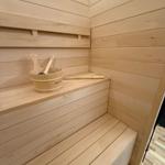 Sauna with wooden bench and bucket with brush.
