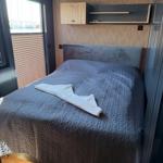 Bedroom with bed, wooden wall, and window overlooking the harbor.