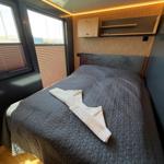Bedroom with bed, wood paneling, and window with blinds.
