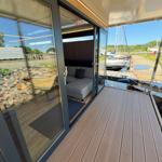 Deck with wooden planks and view of marina. Glass doors lead to interior space.