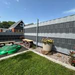 Backyard with playground, flower pot, and stone wall. Lawn and gravel area.