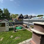 Backyard with playhouse, green seating area, and grill. Backyard with playhouse, green seating area, and grill.