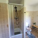 Bad mit Dusche, Toilette und Holzbank.