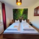 Schlafzimmer mit Doppelbett, Wandbild und Fenster mit Blick.