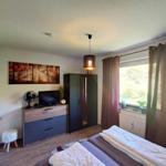 Schlafzimmer mit Bett, Kleiderschrank, TV und Fenster mit Blick auf Grün.