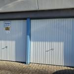 Zwei weiße Garagentore mit Schildern für Gäste
