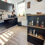 Küche mit schwarzen Schränken, Holzboden und Fenster mit Pflanzen.