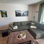 Ein Wohnzimmer mit grauem Sofa, Holztisch und Wandbildern.