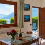 Esszimmer mit Tisch, Stühlen und Blick auf See und Berge.