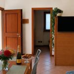 Esszimmer mit Tisch, Stühlen, Blumen und Flasche. Durchgang zu Schlafzimmer und Terrasse.