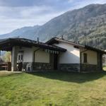 Haus mit Terrasse und Blick auf bewaldete Berge.