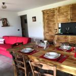Essbereich mit Holztisch, Stühlen und rotem Sofa. Küche mit Holzschränken und schwarzer Arbeitsfläche.