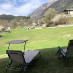 Zwei Liegestühle auf einer Wiese mit Blick auf Berge und Häuser.