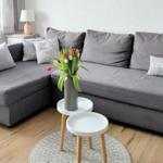 Graße Eckcouch mit Kissen, kleiner Tisch und Blumen im Wohnzimmer.