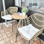 Terrasse mit zwei Stühlen und Tisch. Hintergrund: Fenster und dunkler Holzaufbau.