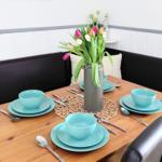 Holztisch mit blauer Geschirrset und Tulpen im Zentrum.