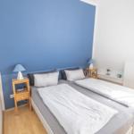 Schlafzimmer mit Doppelbett, blauer Wand und zwei Nachttischen.