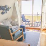 Wohnzimmer mit Sitzgelegenheiten und Balkonblick auf Grasland.