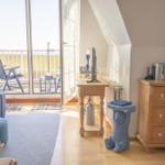 Wohnraum mit Balkon, Schreibtisch, Kommode und blauen Möbeln.