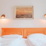 Schlafzimmer mit Holzbett, Wandbild und zwei Wandlampen.