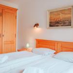 Schlafzimmer mit Holzbett, Kleiderschrank und Wandbild mit Segelschiff.
