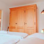 Schlafzimmer mit Bett, Holzschrank und Sicht auf Küche