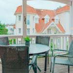 Terrasse mit Tisch und Stühlen. Blick auf ein Gebäude mit rotem Dach.