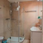 Dusche mit Glaswand, Waschbecken und Heizkörper