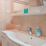 Waschbecken mit Spiegel, Handtuchhalter und Seifenspender.
