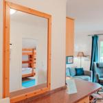 Spiegel zeigt Schlafzimmer mit Doppelstockbett. Wohnbereich mit Sofa, Sessel und Balkon.
