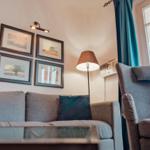 Wohnzimmer mit Sofa, Sessel, Wandbildern und Stehlampe