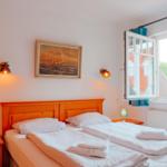 Zimmer mit Doppelbett, Fenster und Wandbild mit Segelschiff.