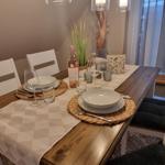 Dining table set for four with a bottle of red wine.