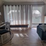 Living area with sofa, table, chairs, and view of balcony.