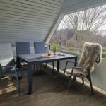 Terrace with table, four chairs, and fur blanket. View of trees and houses.
