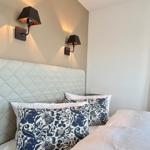 Schlafzimmer mit Bett, Kissen und Wandlampen.