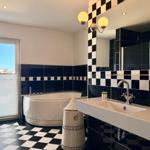 Badezimmer mit Badewanne, Waschbecken und schwarz-weißem Fliesenmuster.