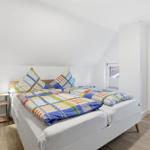Bedroom with double bed, nightstand, and windows.