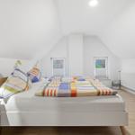 Bedroom with double bed, two windows, and TV.