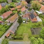 Aerial view of a residential area with red-tiled roofs, green lawns, and neatly trimmed hedges.