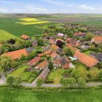 Aerial view of a village with red-tiled roofs, surrounded by green fields and yellow rapeseed.
