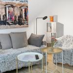 A living room with sofa, cushions, wall art, and tables.