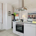 Kitchen with white cabinets, stainless steel stove, and kitchen counter. Windows with view outside.